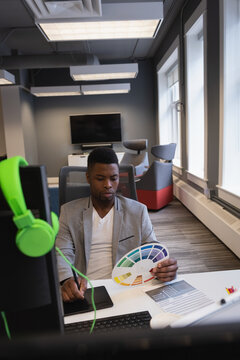 Designer in modern office reviewing color palette while working on digital tablet, copy space