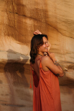 Woman smiling with arms raised in warm sunlight in front of a re