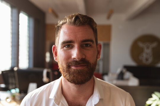 Smiling man with beard working in modern office, enjoying creative environment