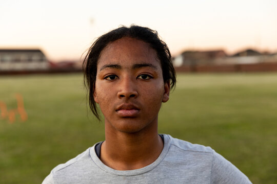 Determined female athlete standing on rugby field during sunset, ready for practice