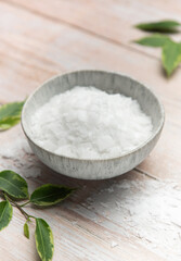 Magnesium flakes in a bowl for a relaxing bath with green leaves decoration