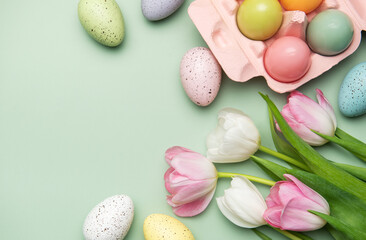 Easter eggs and tulips creating a spring feeling on pastel green background