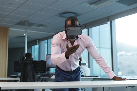 Businessman using VR headset in modern office, interacting with virtual environment
