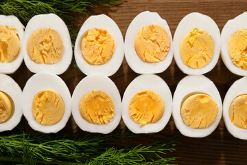 The hard-boiled chicken eggs are cut in half and laid out on a wooden board next to the greens.