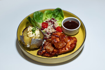 Chicken steak set with sauce, bread and salad plate on a brown wooden table in a restaurant.
