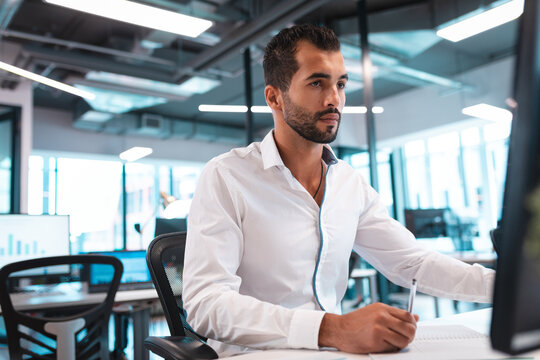 Focused businessman in modern office analyzing data on computer screen