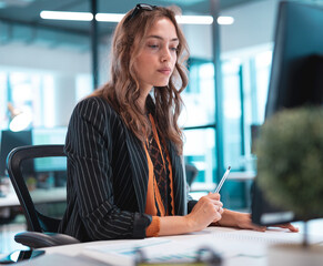 Focused businesswoman analyzing data on computer at modern office desk