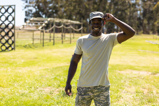 Smiling soldier in camouflage standing confidently on outdoor training field