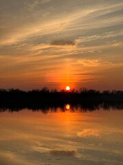 Obraz premium A Beautiful Sunset Over Calm River With Vibrant Orange and Yellow Sky Reflections