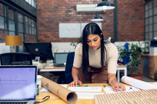 Architect reviewing blueprints in modern office, focusing on project details