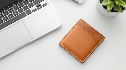 Top view of a modern workspace with a leather wallet, laptop, and plant on a white desk.