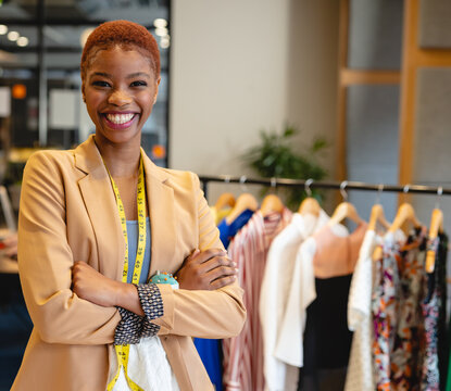 In boutique, fashion designer crossing arms and smiling, showcasing clothing line, copy space
