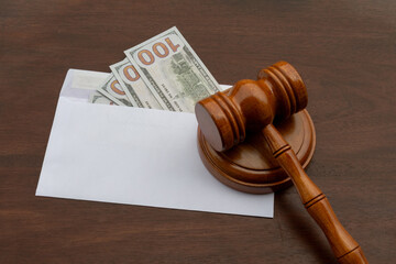 A detailed close-up of a gavel beside a white envelope containing money, symbolizing legal...