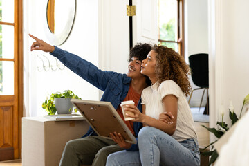 Young diverse couple planning home decor while holding picture frame and coffee cup