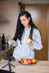 Food blogger showing peeled apple while recording video in kitchen