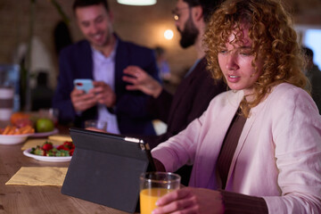 Businesswoman working on tablet while colleagues chatting in background