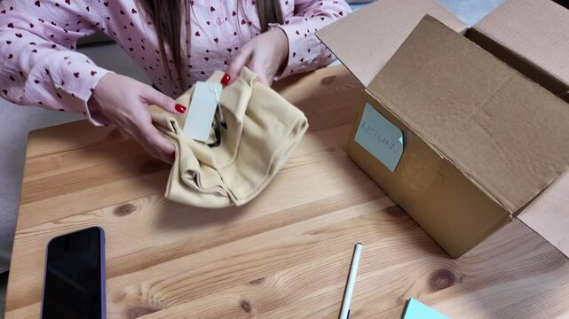 Woman returning clothes by mail using cardboard box, top view