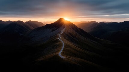 Naklejka premium Dramatic mountain landscape at sunrise. Winding road ascends a peak, bathed in golden light