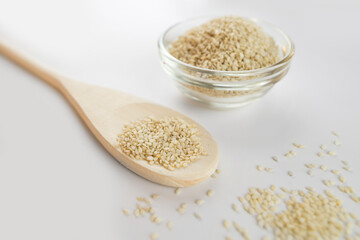 Sesame bowl on a white background. Sesame seeds in a wooden spoon, isolated on a white