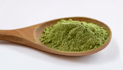 Green kale or basil powder in rustic wooden spoon, white background. Natural spice.