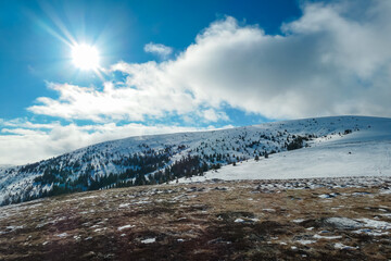 Snowy mountain ridge and peaks covered with snow, extends beneath bright blue sky dotted with fluffy clouds  near Seinerkreuz summit, Packalpe, Styria, Austria. Serene winter landscape, Austrian Alps