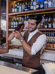 Professional bartender holds in hands steel shaker.
