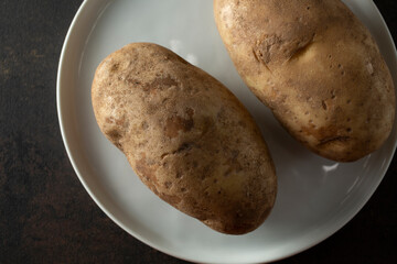 A top down view of a plate of raw russet potatoes.