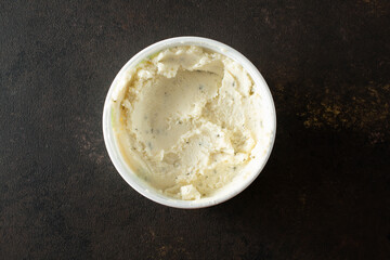 A top down view of a container of garlic and herb dairy-free cheese spread.