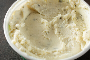 A closeup view of a container of garlic and herb dairy-free cheese spread.