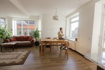 Woman drinking tea and eating a cake in her kitchen