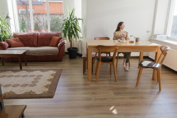 Woman drinking tea and eating a cake in her kitchen