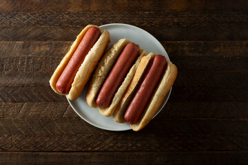 A top down view of a plate of three hot dogs.