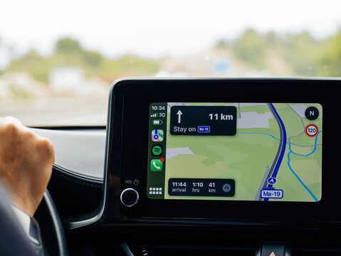 Mallorca, Spain - Jun 28, 2023: A close-up of a car's infotainment screen displaying CarPlay navigation on highway Ma-19 in Mallorca, showing directions, speed limits, and arrival time.