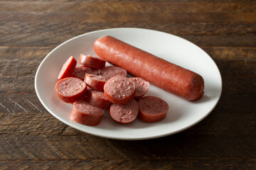 A view of a plate of a whole hot dog and slices of a hot dog.