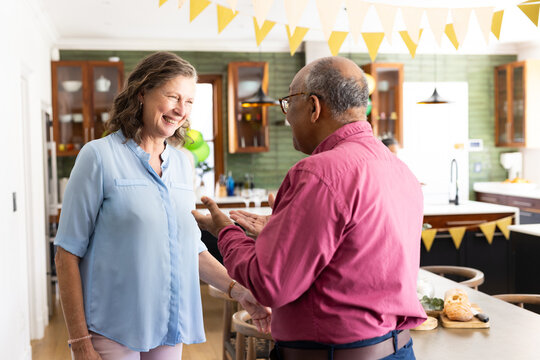 In modern kitchen, diverse senior friends during festive gathering, smiling warmly, at home