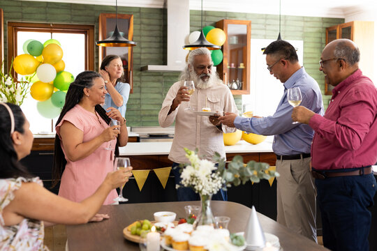 Celebrating at home, senior diverse friends raising glasses, cherishing each other's company