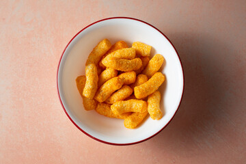 A top down view of a bowl of chickpea based cheese puffs.