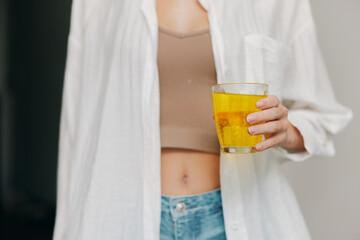 Woman holding glass of orange juice with unbuttoned shirt and cleavage showing