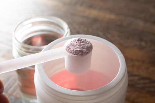 A view of a hand scooping electrolyte powder out of a container.