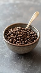 Fototapeta premium Roasted coffee beans in bowl on gray surface