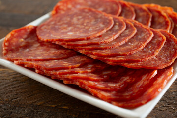A closeup view of a plate of uncured pepperoni slices.