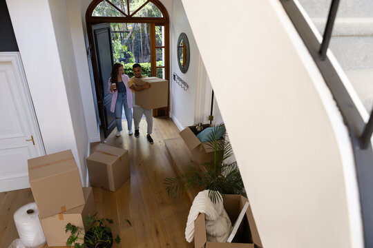 Young diverse couple carrying boxes into new home, starting fresh chapter together