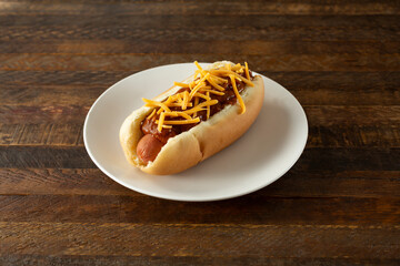 A view of a chili cheese dog on a plate.