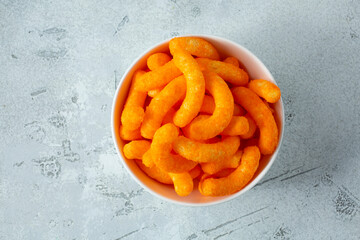 A top down view of a bowl of cheese puff chips.