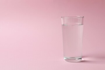 Glass of water on color background