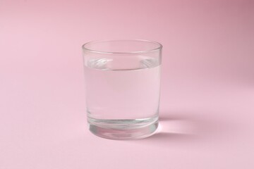 Glass of water on color background