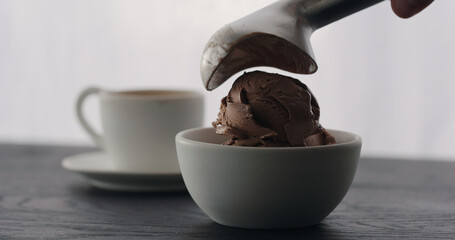 put chocolate ice cream into white bowl with espresso on black wood table