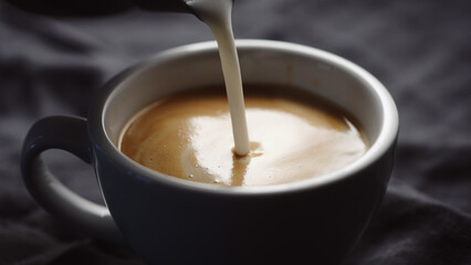 pour steamed milk into white cup making cappuccino