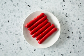 A top down view of red hot dogs, on a plate.