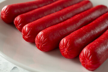 A closeup view of red hot dogs, on a plate.